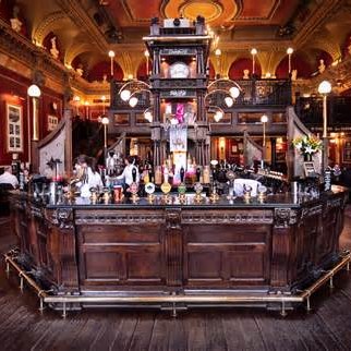 The interior of a pub with a dark wood bar area and lots of LED lights in the ceiling and around the bar